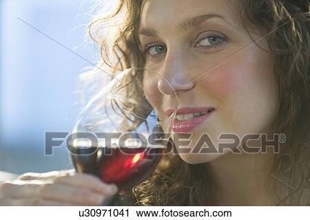 Stock Image - Close up portrait of woman smelling red wine. Fotosearch