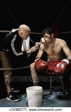 Stock Image - Coach talking to boxer in corner of boxing ring. Fotosearch