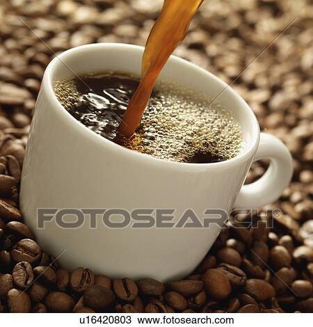 Stock Image - Coffee pouring into mug surrounded by coffee beans. Fotosearch