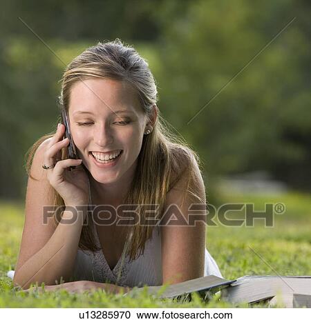 College student reading in grass and talking on cell phone View Large Photo Image Stock Image - College student reading in grass and talking on cell phone. Fotosearch