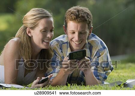 College students laying in grass with books and cell phones View Large Photo Image Stock Image - College students laying in grass with books and cell phones. Fotosearch