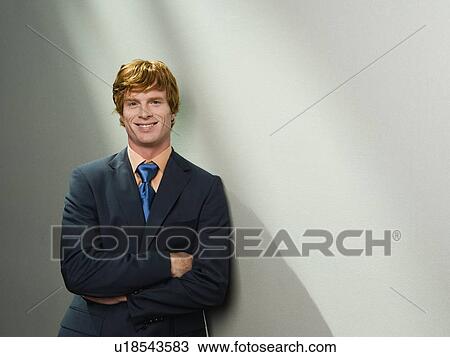 Stock Image - Confident businessman leaning against wall. Fotosearch