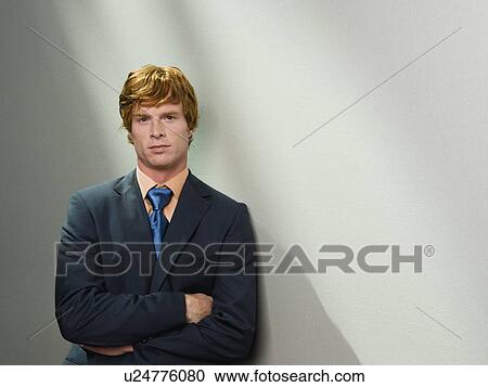 Stock Image - Confident businessman leaning against wall. Fotosearch