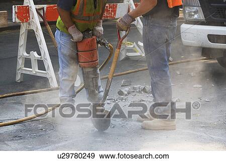 Stock Photo - Construction workers using jackhammer and shovel. Fotosearch