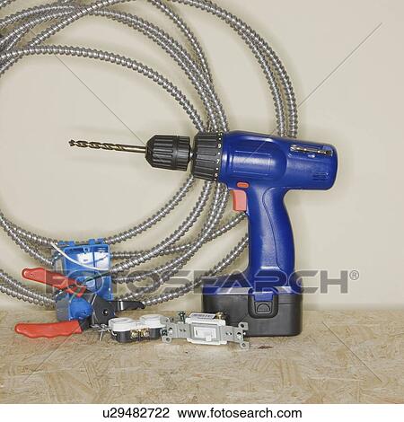Stock Image - Cordless drill next to wire cutters and cable. Fotosearch