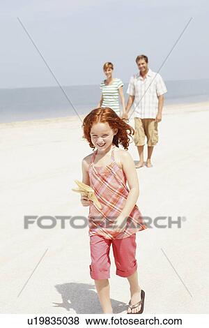 Stock Photo - Couple and daughter walking on beach. Fotosearch