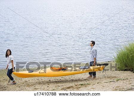 Stock Photo - Couple carrying kayak. Fotosearch