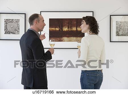 Couple discussing art at art gallery View Large Photo Image Stock Photograph - Couple discussing art at art gallery. Fotosearch
