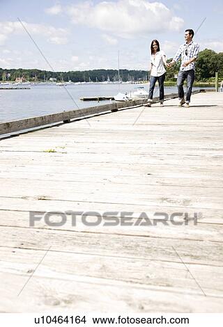 Couple holding hands and walking on dock View Large Photo Image Picture - Couple holding hands and walking on dock. Fotosearch