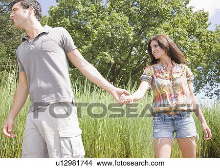 Couple holding hands and walking through reeds View Large Photo Image Picture - Couple holding hands and walking through reeds. Fotosearch