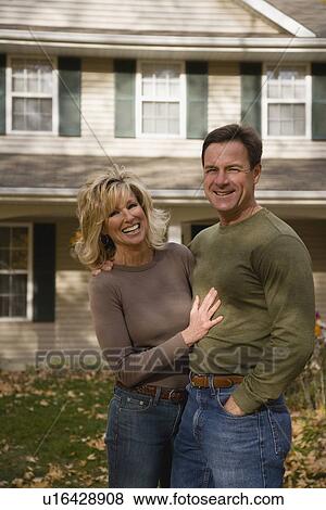 Stock Photo - Couple hugging in front of house. Fotosearch