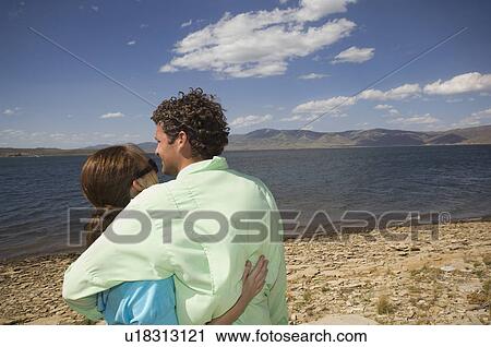 Stock Image - Couple hugging in front of lake, Utah, United States. Fotosearch