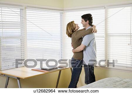 Picture - Couple hugging next to window. Fotosearch