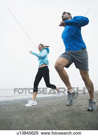 Stock Photo - Couple jogging on beach. Fotosearch