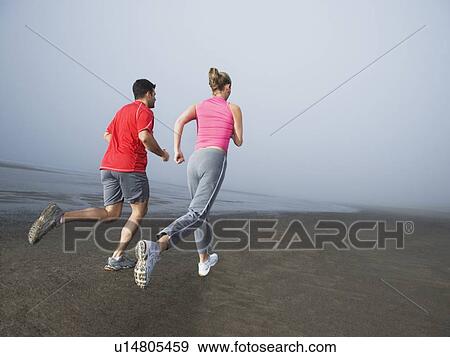 Stock Photo - Couple jogging on foggy beach. Fotosearch