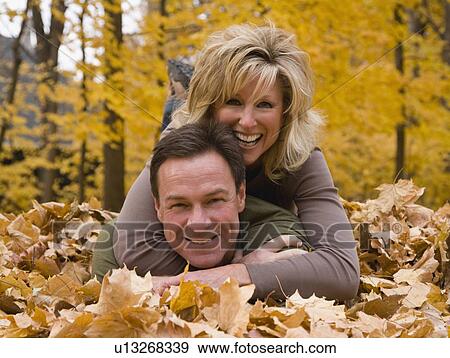 Couple laying in autumn leaves View Large Photo Image Stock Photo - Couple laying in autumn leaves. Fotosearch