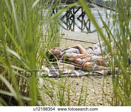 Couple laying on blanket near lake View Large Photo Image Picture - Couple laying on blanket near lake. Fotosearch