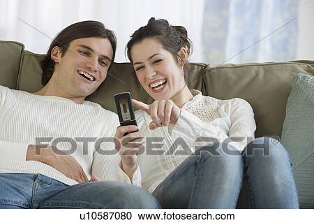 Stock Image - Couple looking at cell phone. Fotosearch