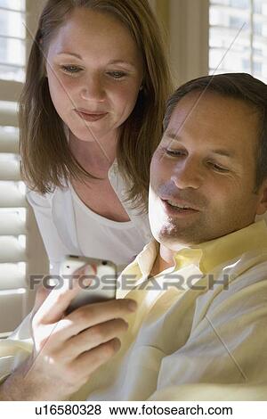 Couple looking at cell phone View Large Photo Image Stock Photo - Couple looking at cell phone. Fotosearch