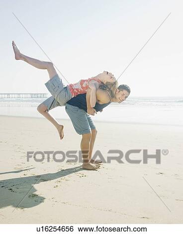 Stock Photograph - Couple playing around on beach. Fotosearch