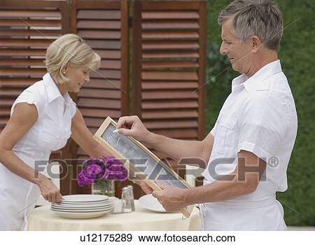 Couple preparing outdoor restaurant for service View Large Photo Image Stock Photo - Couple preparing outdoor restaurant for service. Fotosearch