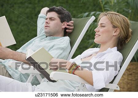 Couple reading in lounge chairs View Large Photo Image Stock Photograph - Couple reading in lounge chairs. Fotosearch