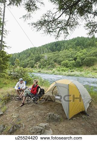 Couple relaxing at campsite View Large Photo Image Stock Image - Couple relaxing at campsite. Fotosearch