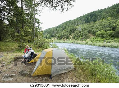 Stock Image - Couple relaxing at campsite. Fotosearch