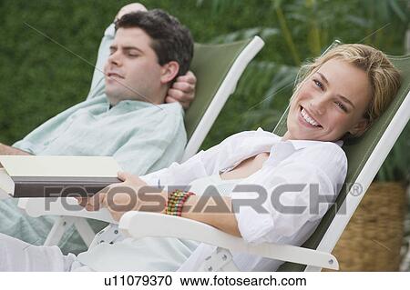 Couple relaxing in lounge chairs View Large Photo Image Stock Image - Couple relaxing in lounge chairs. Fotosearch