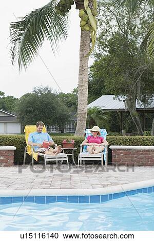 Couple relaxing poolside View Large Photo Image Stock Image - Couple relaxing poolside. Fotosearch