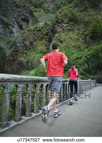 Couple running across bridge View Large Photo Image Stock Photo - Couple running across bridge. Fotosearch