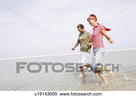 Couple running in ocean View Large Photo Image Stock Photography - Couple running in ocean. Fotosearch