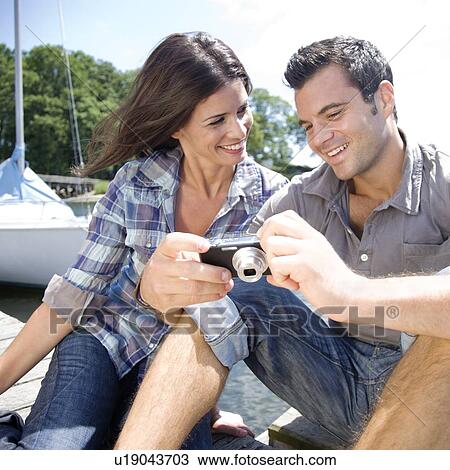 Couple sitting on dock looking at photos on digital camera View Large Photo Image Stock Image - Couple sitting on dock looking at photos on digital camera. Fotosearch