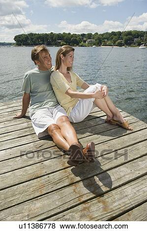 Couple sitting on dock View Large Photo Image Stock Photo - Couple sitting on dock. Fotosearch