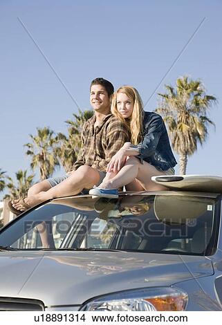 Picture - Couple sitting on top of car. Fotosearch