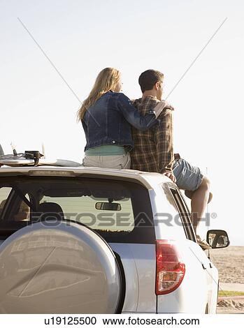 Couple sitting on top of car View Large Photo Image Stock Image - Couple sitting on top of car. Fotosearch