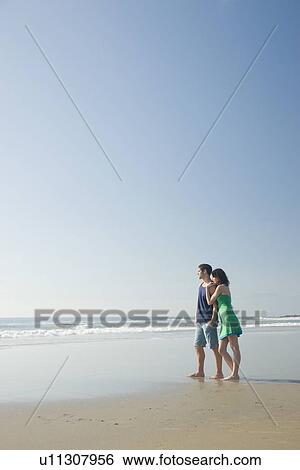 Stock Photograph - Couple standing on beach. Fotosearch