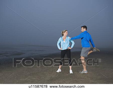 Stock Photo - Couple stretching on beach. Fotosearch