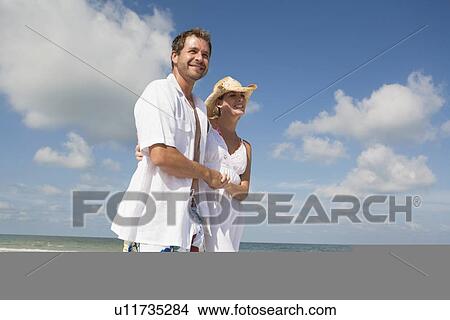 Picture - Couple walking on beach. Fotosearch