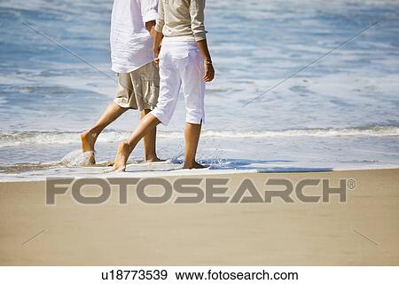 Stock Photo - Couple walking on beach. Fotosearch