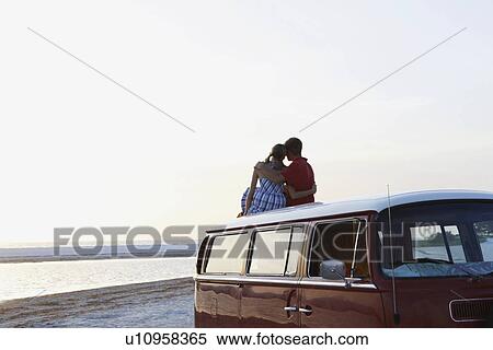 Couple watching ocean sunset from top of van View Large Photo Image Stock Photography - Couple watching ocean sunset from top of van. Fotosearch
