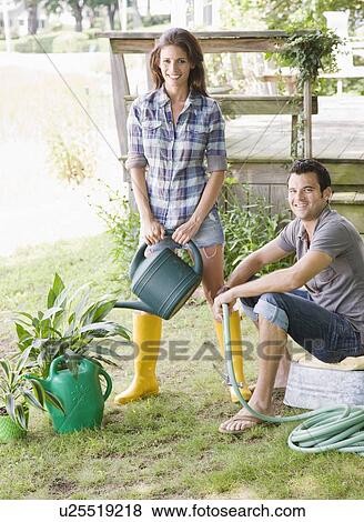 Couple watering plants in backyard View Large Photo Image Stock Photo - Couple watering plants in backyard. Fotosearch
