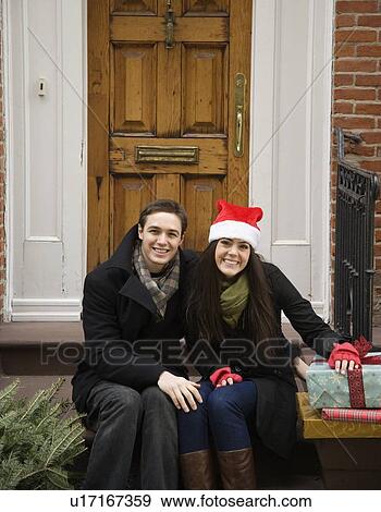 Couple with Christmas tree and gifts in front of door View Large Photo Image Stock Photo - Couple with Christmas tree and gifts in front of door. Fotosearch