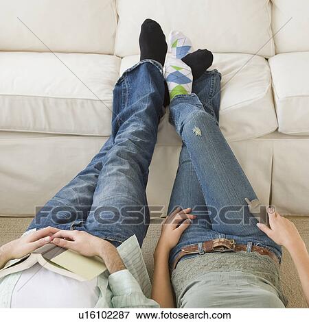 Stock Photo - Couple with feet up on sofa. Fotosearch