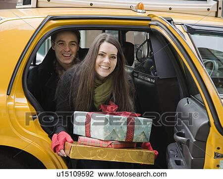 Stock Image - Couple with gifts getting out of taxi cab. Fotosearch