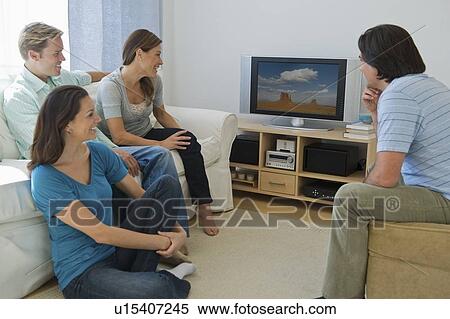 Couples watching television in living room View Large Photo Image Stock Photography - Couples watching television in living room. Fotosearch