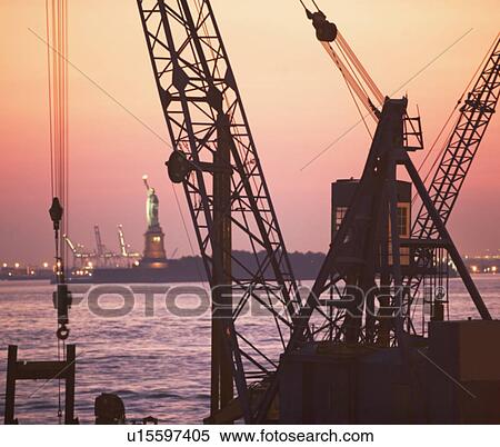 Stock Photography - Crane with Statue of Liberty in background, New York, United States. Fotosearch