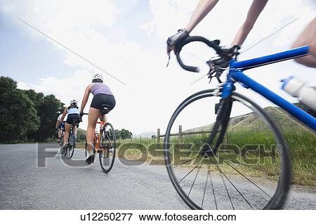 Stock Photo - Cyclists in a row on country road. Fotosearch