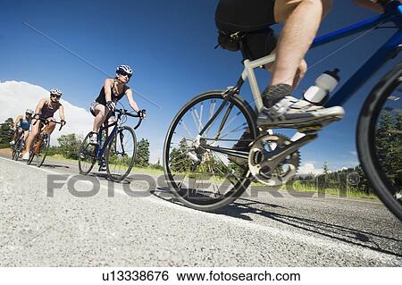 Cyclists in a row on mountain road View Large Photo Image Stock Photograph - Cyclists in a row on mountain road. Fotosearch