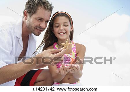 Daughter showing starfish to father View Large Photo Image Stock Image - Daughter showing starfish to father. Fotosearch